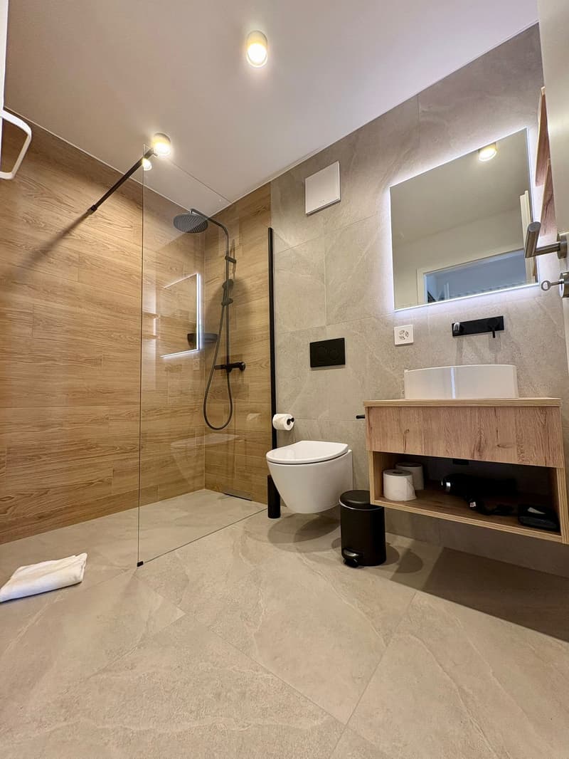 Modern design, floor-to-ceiling shower enclosure, wooden walls, white tiles, double vanity with two sinks, glass and wood finishes