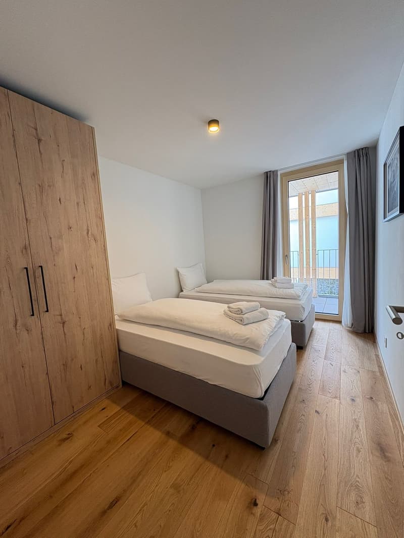 wooden floor, large windows, two single beds, balcony, wooden wardrobe, gray bedding