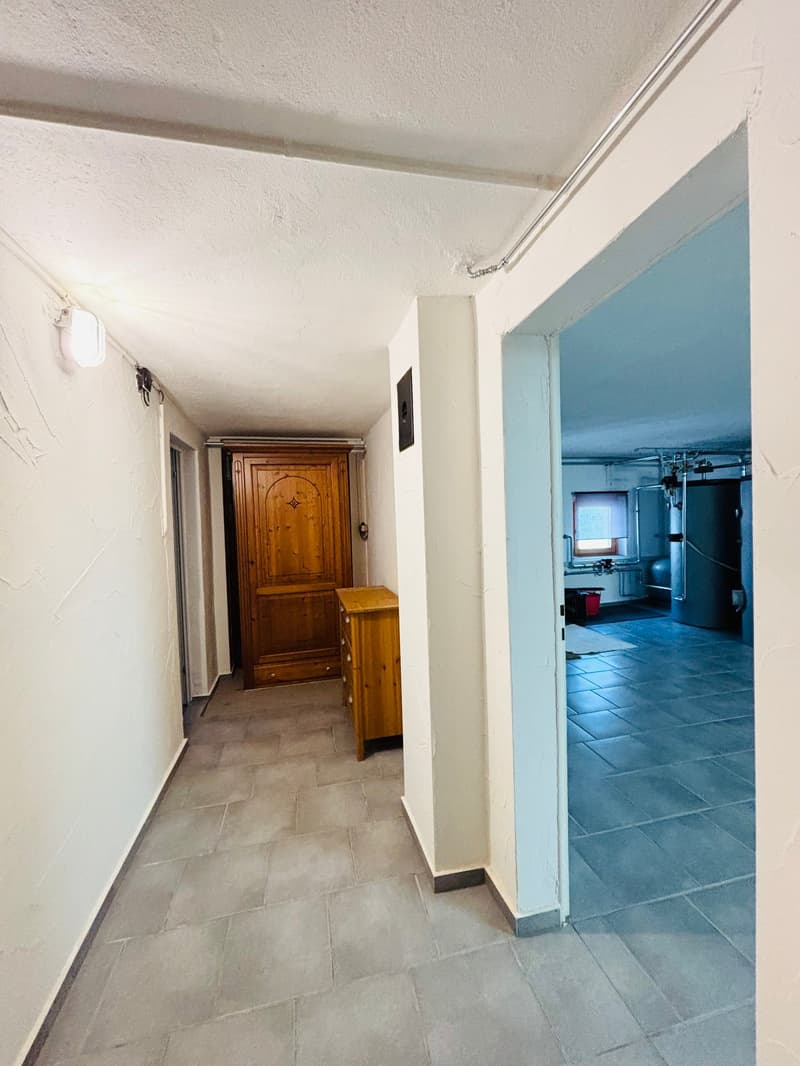 Empty hallway with tiled floor, wooden cabinet, and a door leading to another room