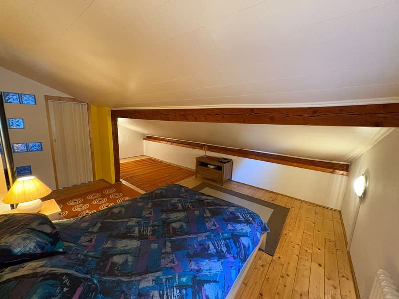 bedroom with wooden floor, bed, lamp, nightstand, rug, wooden beams, yellow wall, white ceiling