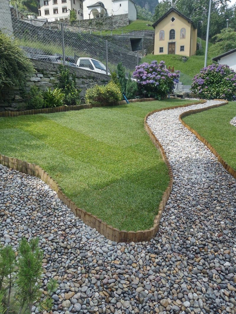 green lawn, gravel path, stone wall, plants, flowers, small trees