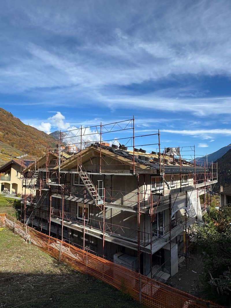 a two story house under construction, surrounded by orange fences and scaffolding