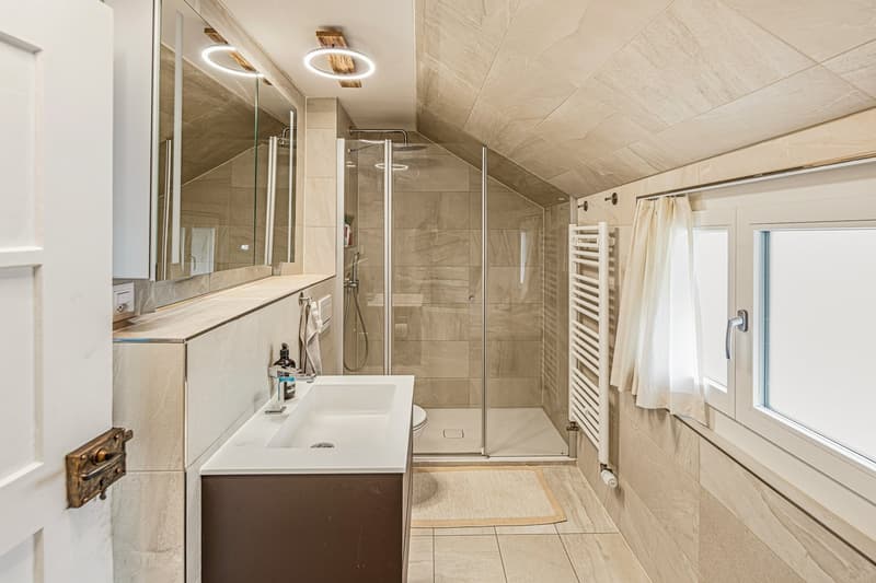 modern bathroom with shower, sink, toilet, mirror, window, wooden floor, beige tiles