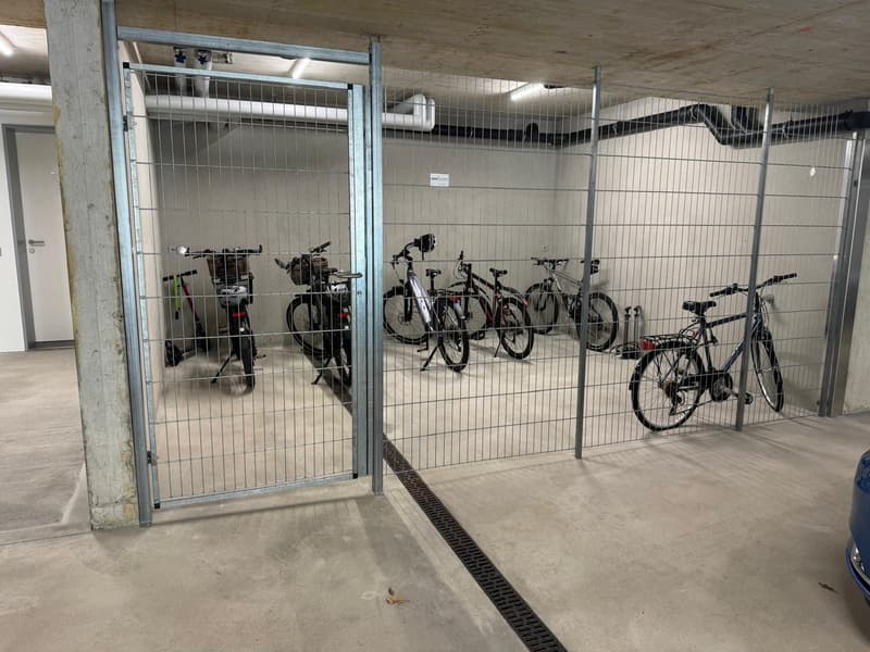 underground parking area with several bicycles parked in a fenced area
