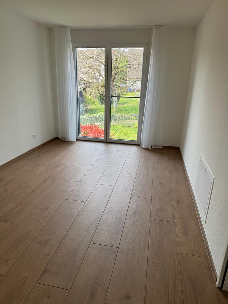 empty room, wooden floor, sliding glass door, white walls, white curtains, power outlet, view of garden