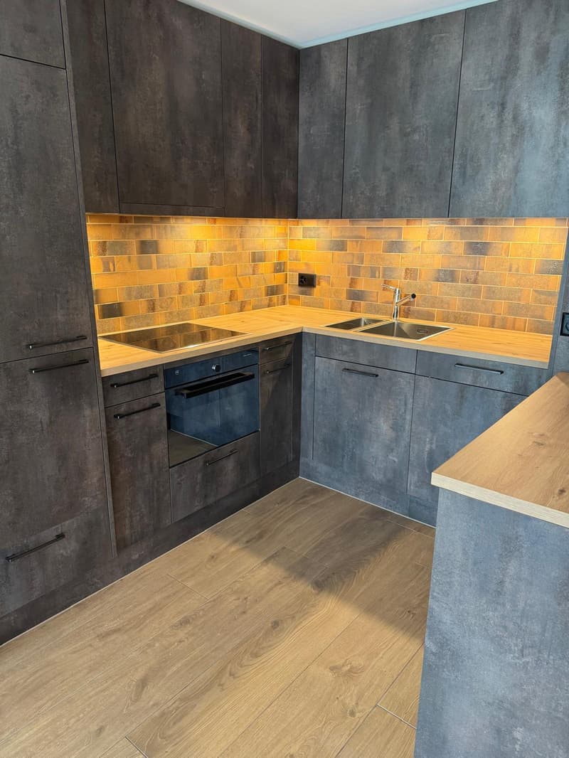 modern kitchen with gray cabinets, wooden countertops, gas stove, oven, sink, faucet, tiled backsplash, wooden floor