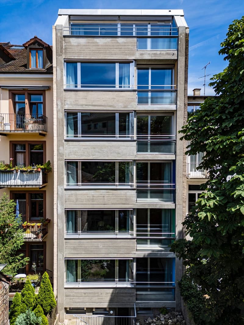 Modern apartment building, concrete exterior, large windows, balconies, multiple floors