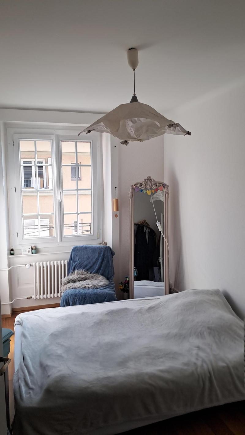bedroom with bed, chair, mirror, window, radiator, lamp