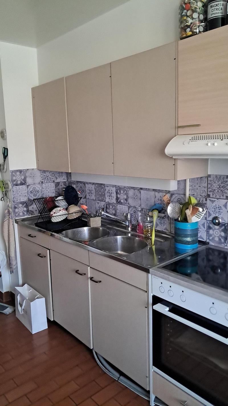 kitchen with sink, stove, oven, cabinets, tiled wall, utensils