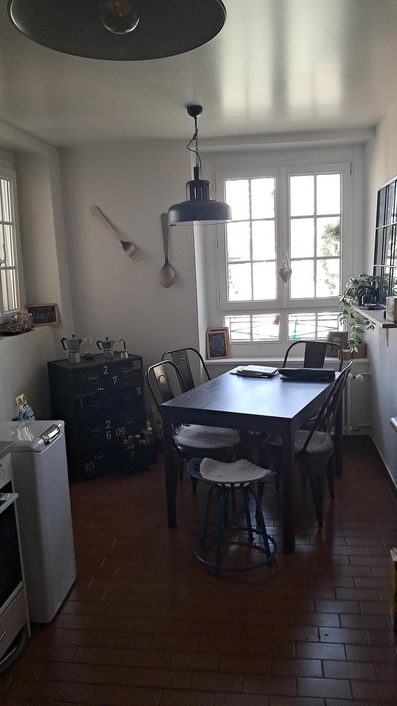 Dining room with wooden floor, dining table, chairs, cabinet, radiator, windows, and a lamp