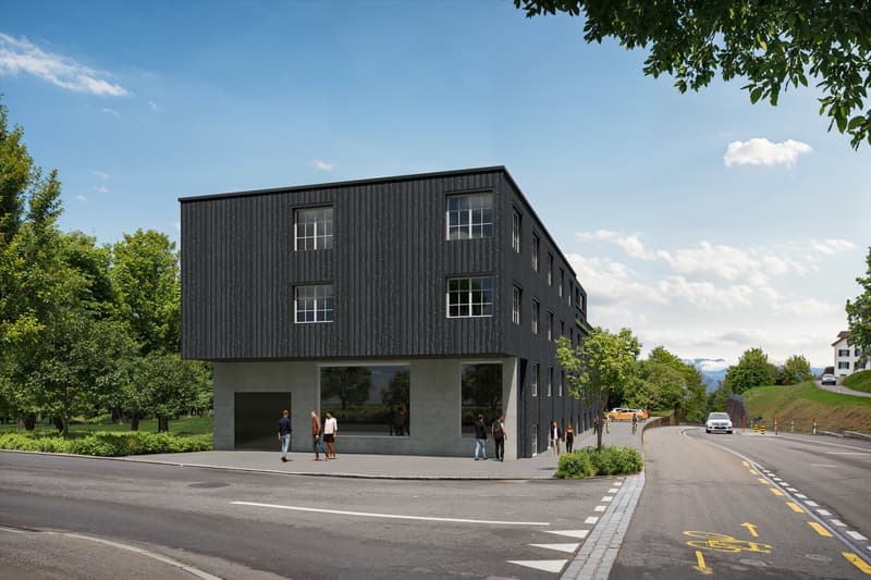 2-story building with modern architectural design, glass windows, large entrance, flat roof, situated near road, greenery, parking space in front