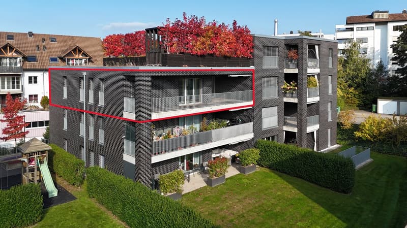 2 story apartment building, black bricks, red border, multiple balconies, garden area