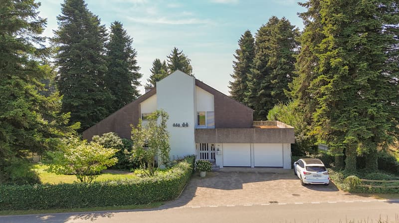 A modern architectural house with brown and white exterior, roof terrace, driveway, and a car parked