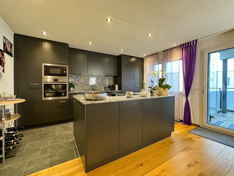 modern kitchen with built-in appliances, granite countertops, island with breakfast bar, wooden flooring, open door to balcony