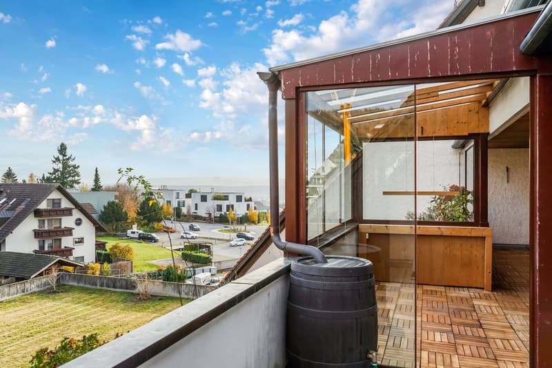 balcony, glass windows, gutter, barrel, grassy field, residential buildings, view of mountains