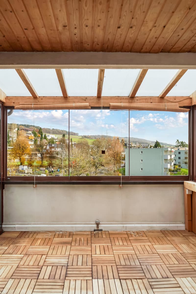 room with wooden floor, large glass window overlooking a view of the town