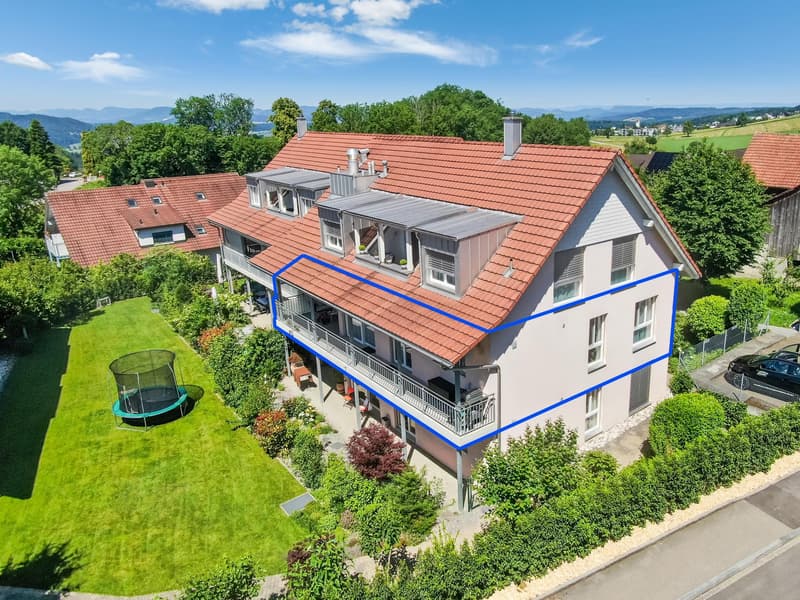 3-story house with red tile roof, white exterior, multiple balconies, surrounded by lush greenery and trees, with a trampoline in the yard