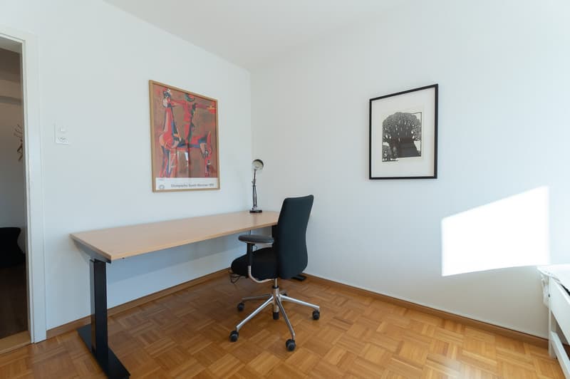 Desk, office chair, table lamp, two framed pictures, wooden floor