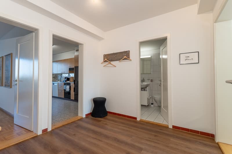 wooden floor, white walls, open plan with kitchen, entrance hall, wooden hangers, small stool, modern furniture