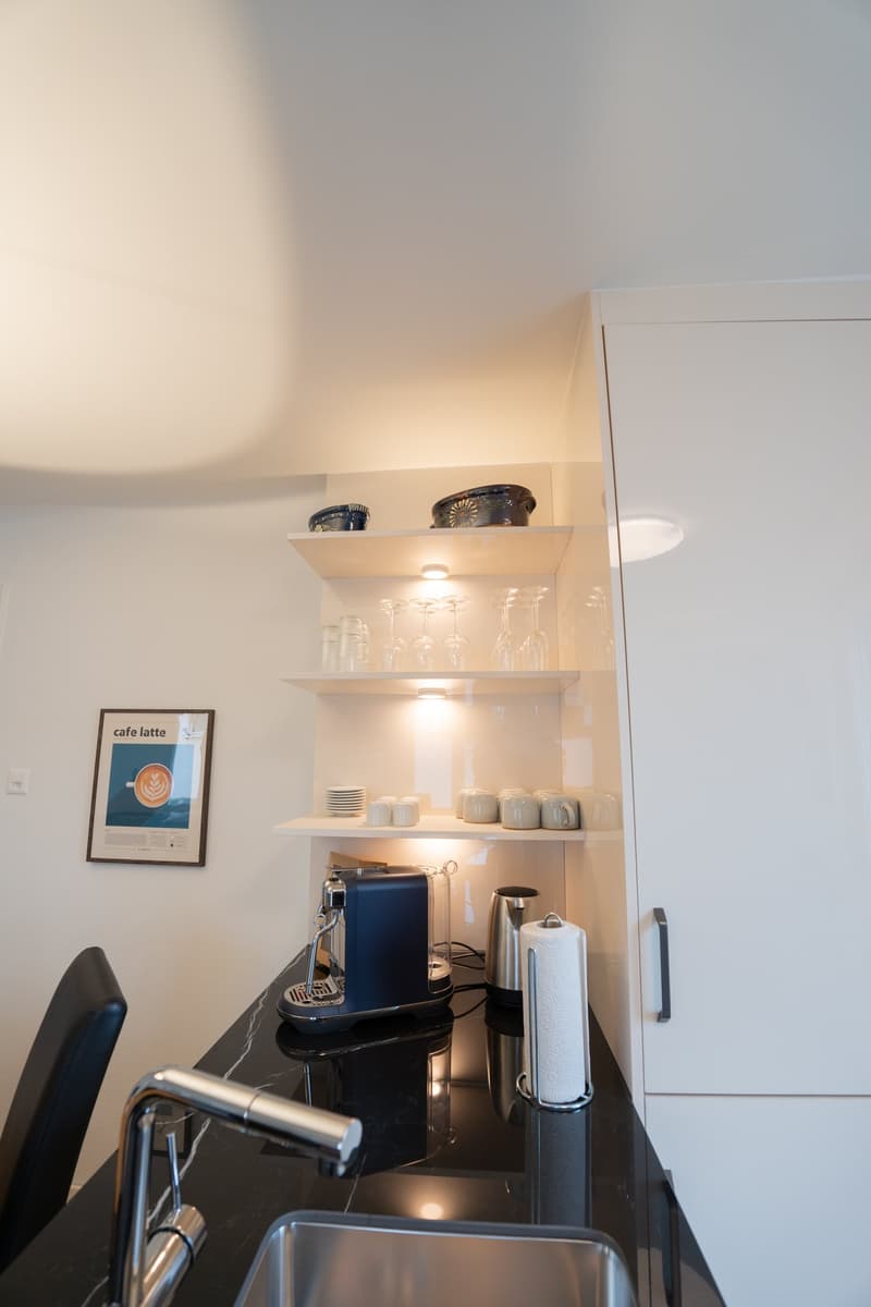 Compact kitchen with white shelves, coffee maker, and other kitchen appliances