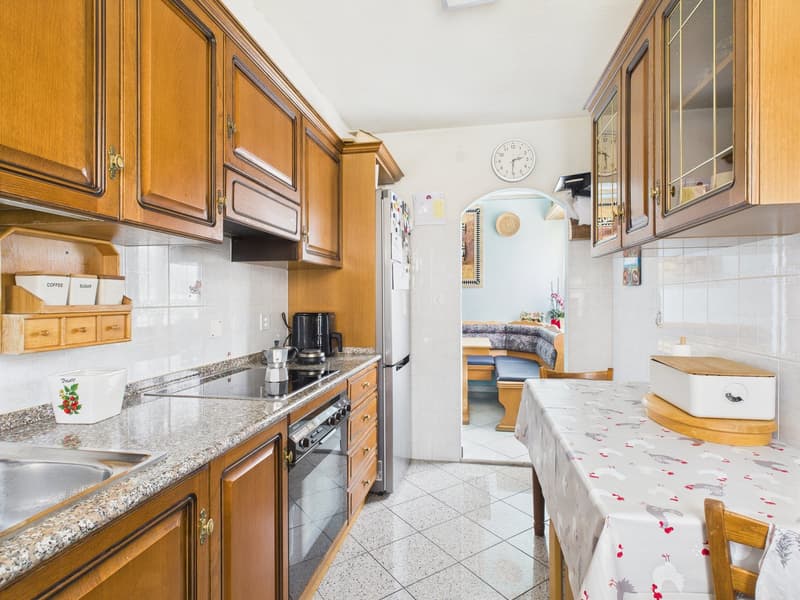 Spacious kitchen with wooden cabinets, granite countertops, stove, refrigerator, and dining area with a table and chairs