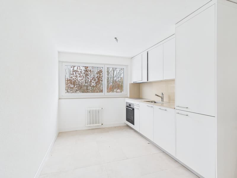 empty modern kitchen with white tiles, modern cabinets, sink, dishwasher, built-in oven, and large window