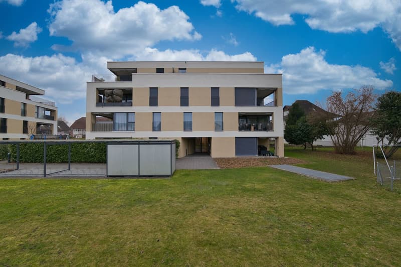 modern architectural design, beige exterior, balconies on multiple floors, well-manicured lawn