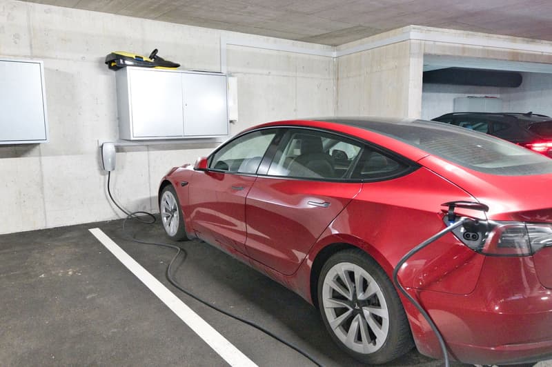 Red Tesla car charging in underground parking garage