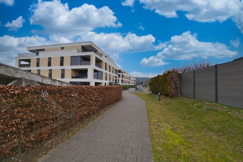 2 story building with beige and white exterior, fenced garden area with sidewalk