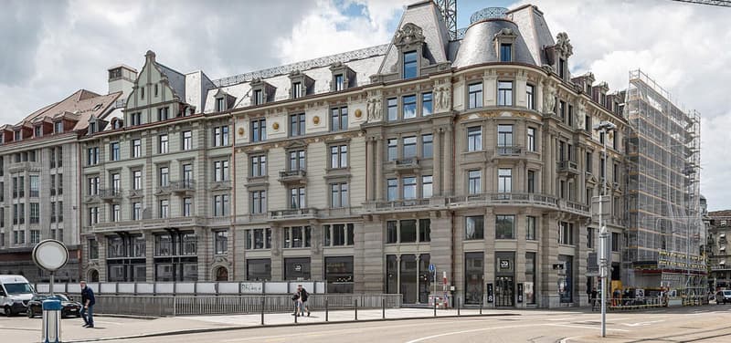Large building with multiple floors, ornate architectural details, multiple windows, balconies, and sculptures