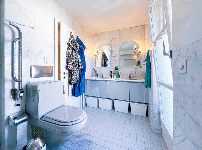 modern bathroom, white tiles, white toilet, white cabinets, double sink, mirrors, towel racks, storage bins