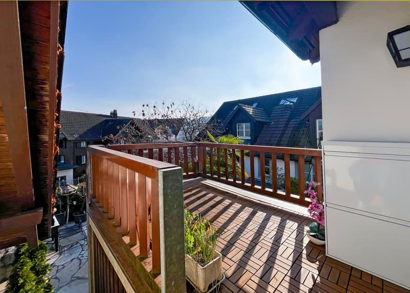 wooden railing, wooden floor, potted plants, white cabinet, view of houses