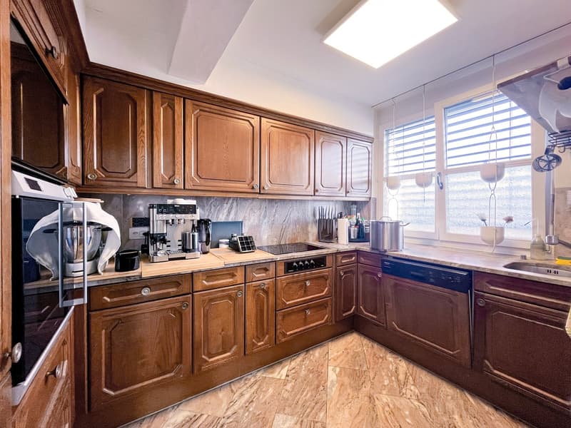 modern kitchen with wooden cabinets, marble countertop, built-in appliances, large window with blinds