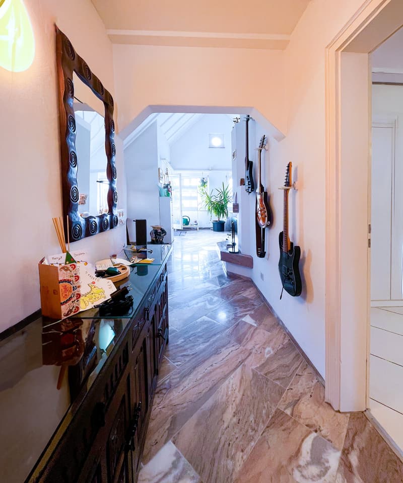 marble floor, wooden cabinet, mirror, guitars on wall, potted plant, hallway