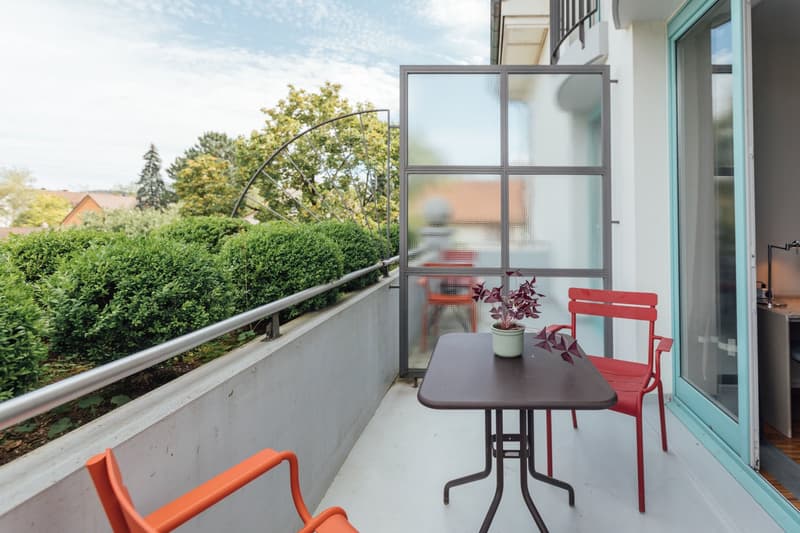 balcony, table, two red chairs, a potted plant, sliding glass door