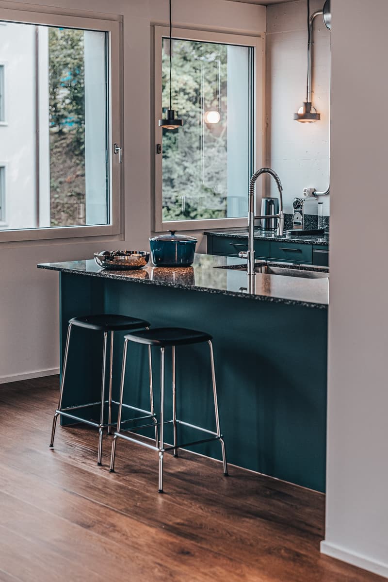 modern kitchen with large windows, kitchen island, bar stools, stovetop and sink