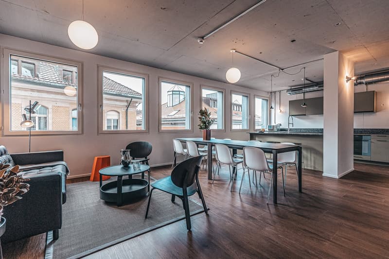 open plan living room and kitchen, large windows, wooden floor, a couch and coffee table