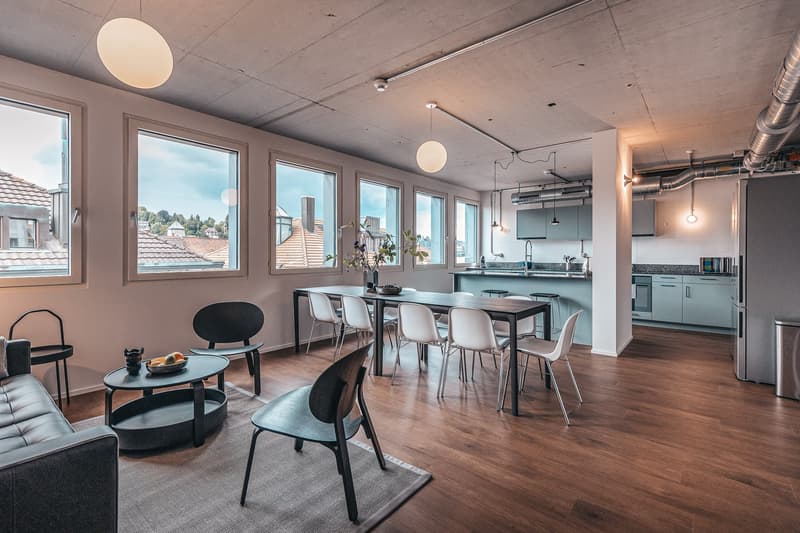modern open space, large windows, wooden floor, kitchen, dining table with chairs, couch, side table, carpet, refrigerator