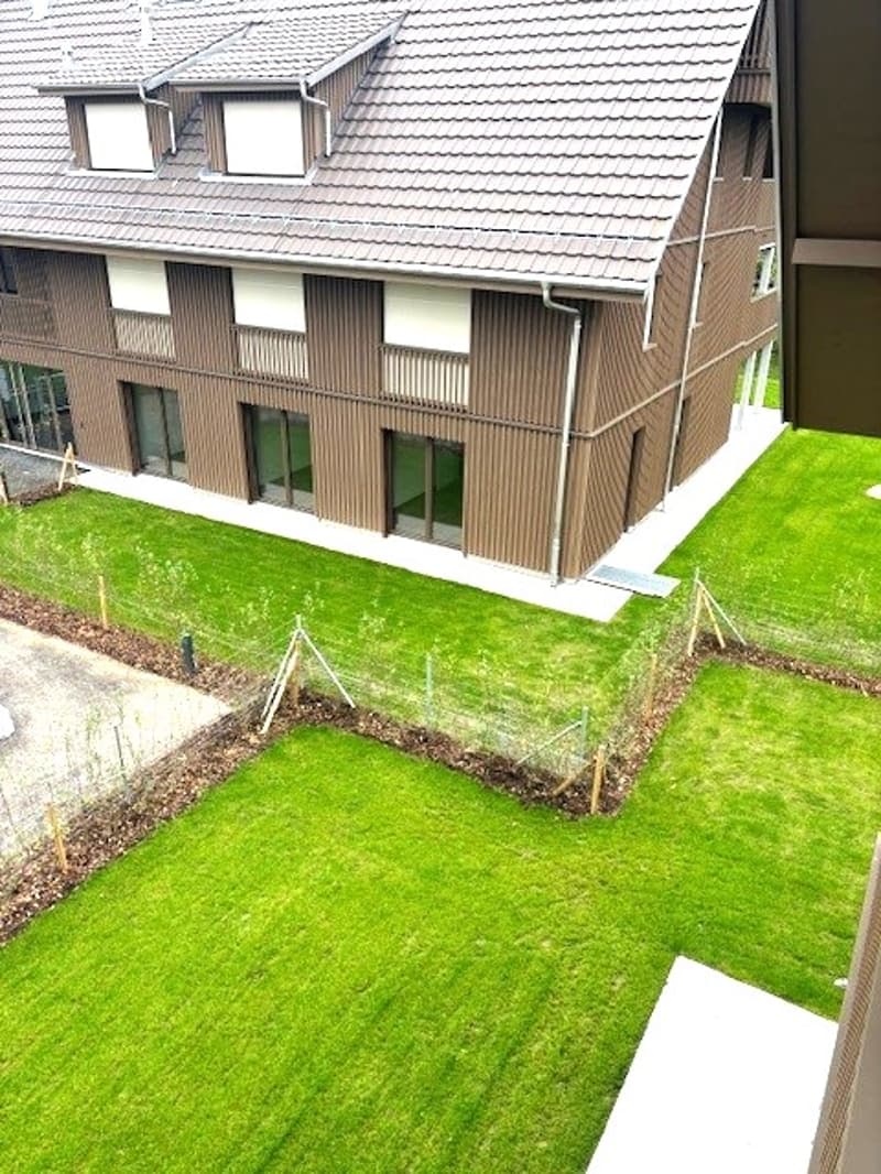 Brown house, multiple windows, green lawn, driveway