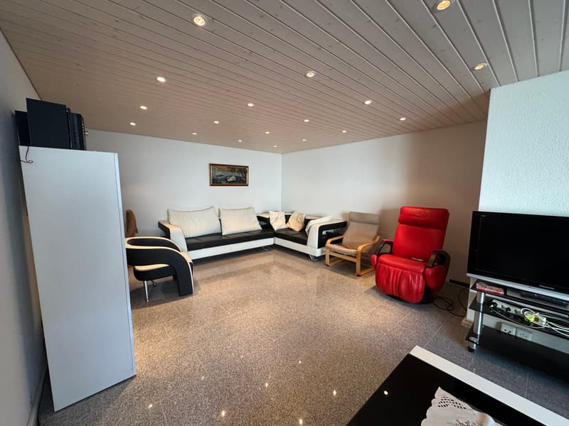 Living room with a couch, armchairs, a television, and a refrigerator