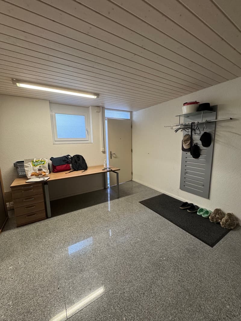 Empty room with desk, storage box, bags, and coat rack