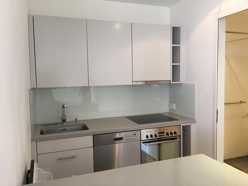modern kitchen with white cabinets, stainless steel appliances, glass backsplash, and a countertop