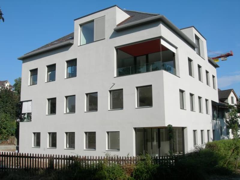 3 story white house, many windows, balcony on the second floor