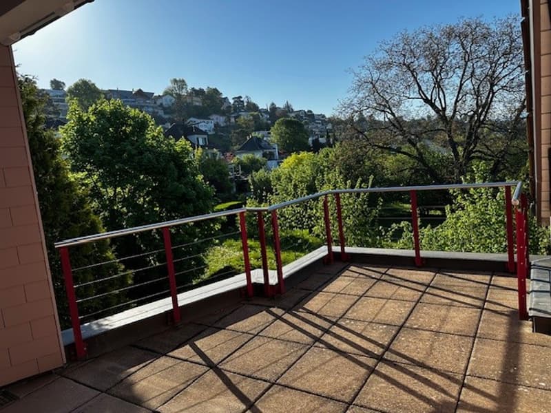 Terrace with a tiled floor, red railing, a beautiful view of a city in the distance