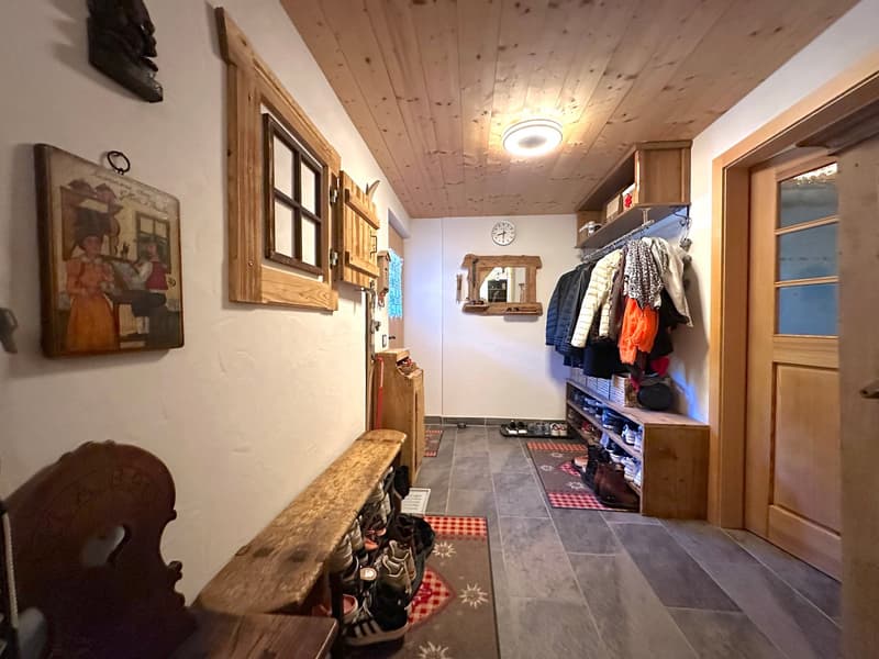Entryway with shoe storage, a wooden bench, closets, and a mirror with a clock. Picture frame hanging on the wall.