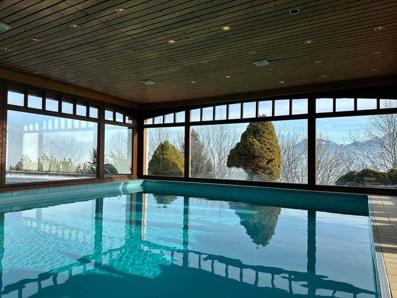 indoor pool, large windows, wooden ceiling, tile flooring, view of mountains