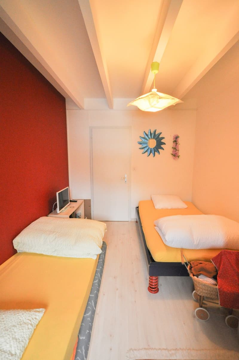 room with two beds, red wall, computer, basket, light