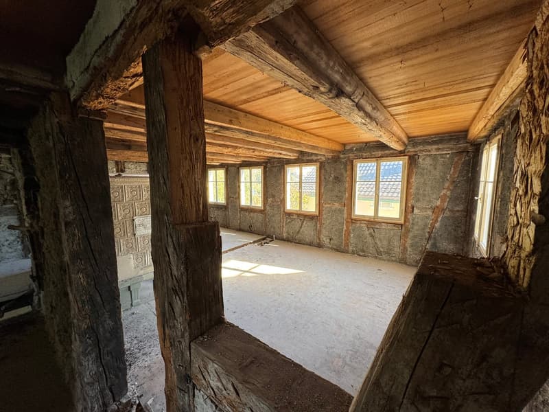 room under construction, wooden beams, walls made of bricks, windows, empty floor