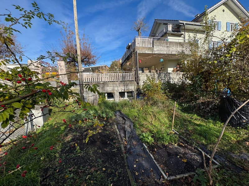 Two story house, balcony, brick walls, yard, and garden.