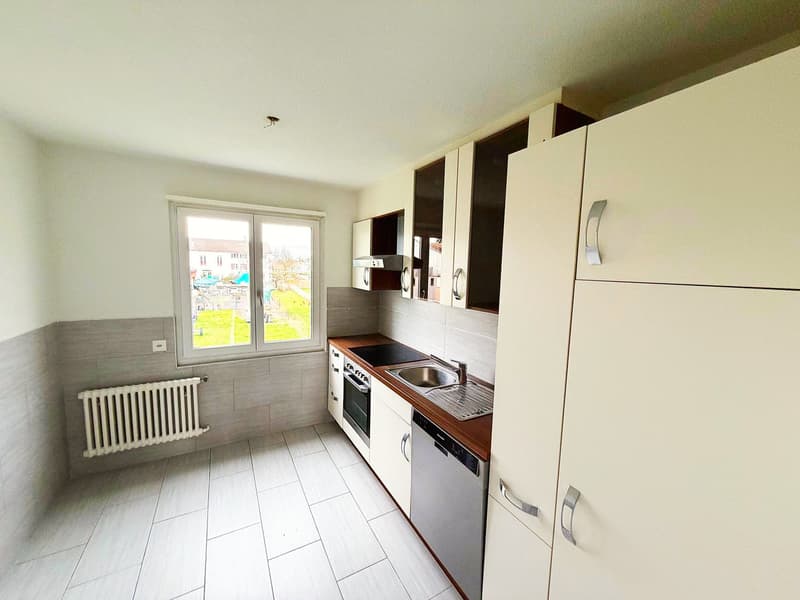 modern kitchen with white tiles, wooden countertops, white cabinets, stainless steel sink, dishwasher, electric oven, and a window with a view